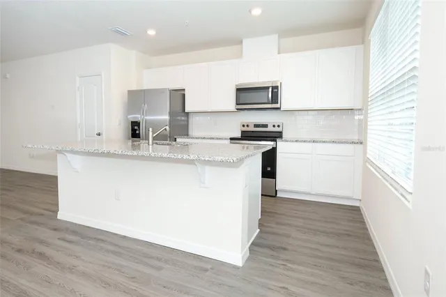 a kitchen with stainless steel appliances granite countertop a stove a sink and a microwave