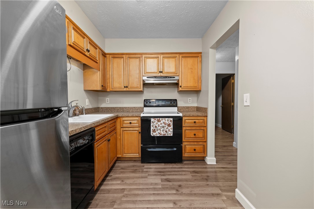 29379 Detroit Road Westlake, OH 44145 - Photo 2 of 23 refrigerator, range with electric stovetop, dishwasher, light wood-style flooring, and a textured ceiling