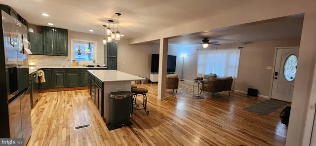 a kitchen with stainless steel appliances granite countertop a refrigerator a sink dishwasher a stove and a dining table with wooden floor