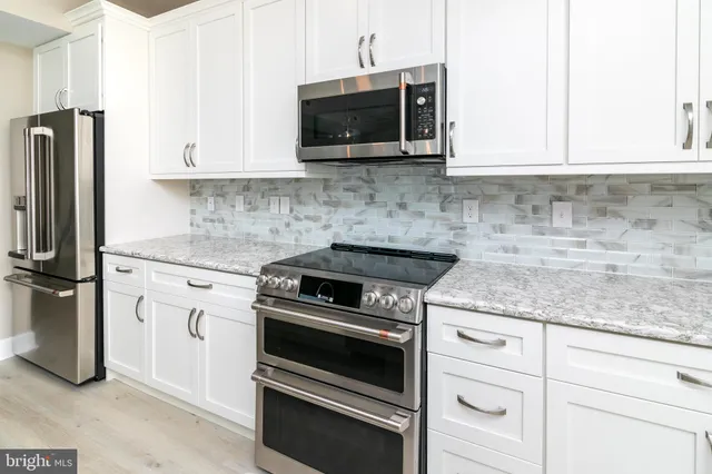 a kitchen with granite countertop white cabinets and stainless steel appliances
