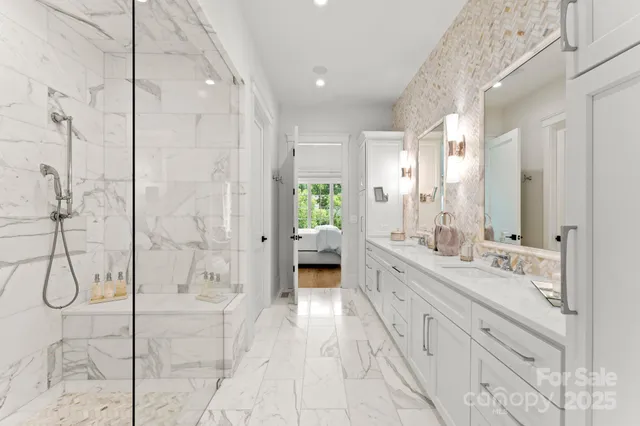 a spacious en suite bathroom with a double vanity sink a large mirror and shower