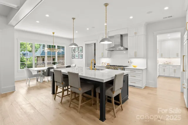 a kitchen with stainless steel appliances granite countertop a stove a refrigerator a kitchen island a table and chairs