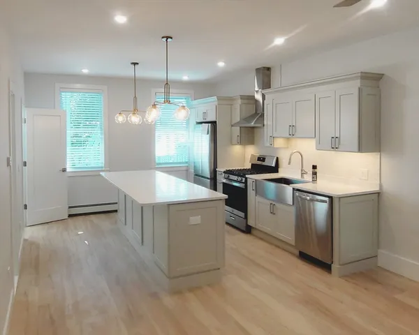 a kitchen with stainless steel appliances granite countertop a sink a stove a refrigerator and island with wooden floor