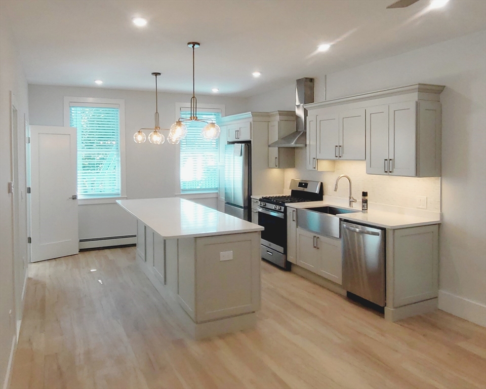 53 West Eagle Street, Unit 2 Boston, MA 02128 - Photo 2 of 7 a kitchen with stainless steel appliances granite countertop a sink a stove a refrigerator and island with wooden floor