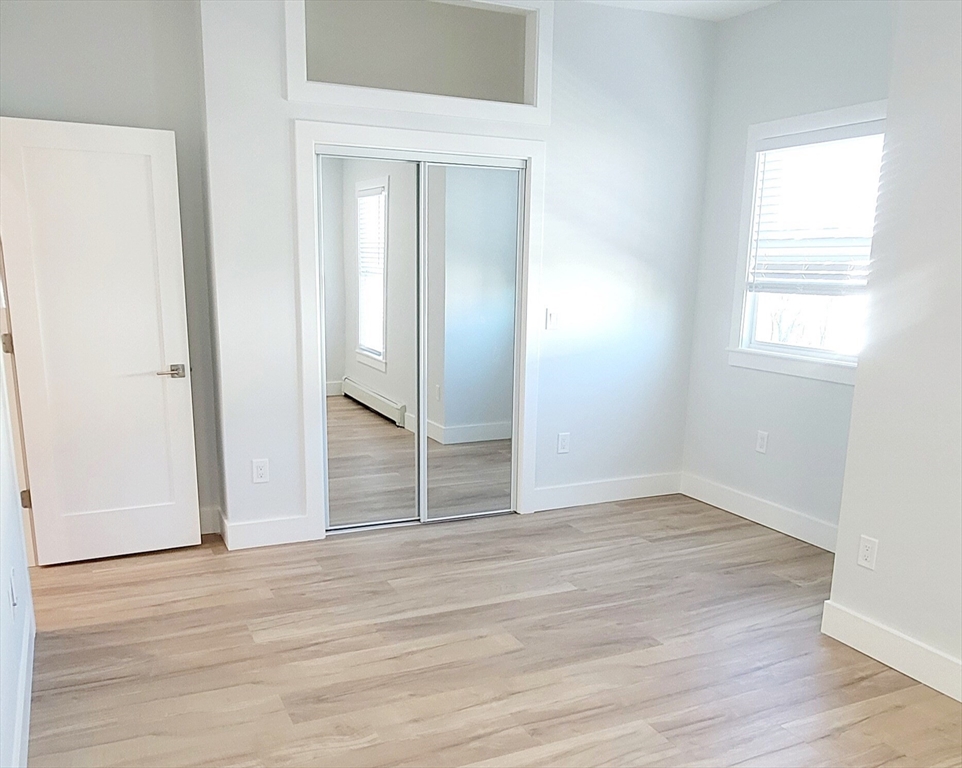 53 West Eagle Street, Unit 2 Boston, MA 02128 - Photo 5 of 7 an empty room with wooden floor closet and windows