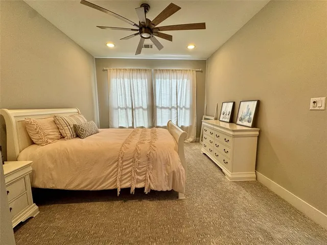 a spacious bedroom with a bed a dresser and a window