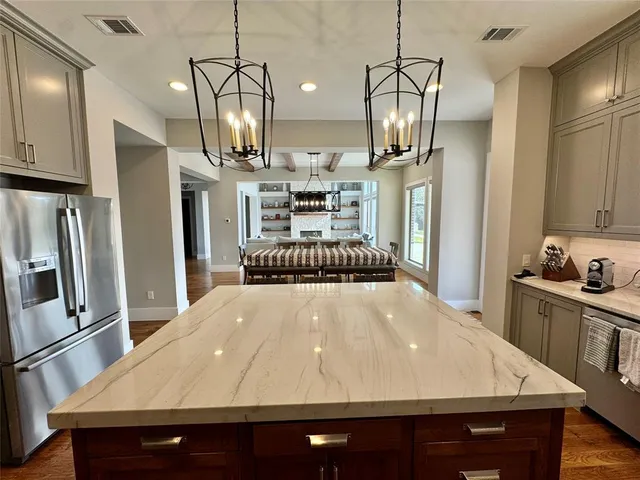 a kitchen with stainless steel appliances a dining table chairs stove refrigerator and cabinets