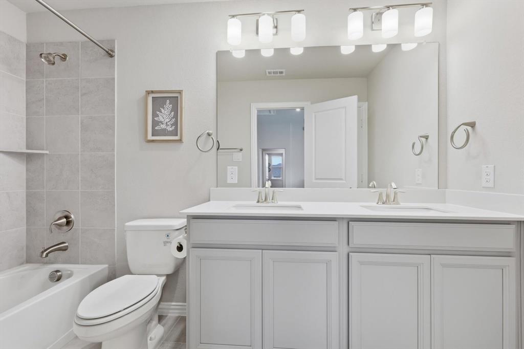 4125 Caprock Canyon Road Sachse, TX 75048 - Photo 25 of 40 a bathroom with a toilet a sink and mirror
