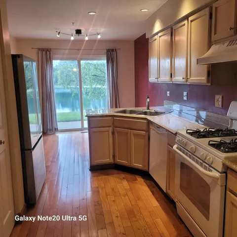a kitchen with stainless steel appliances granite countertop wooden cabinets a stove a sink and a large window