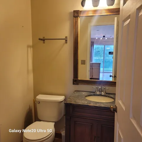 a bathroom with a granite countertop toilet sink and mirror