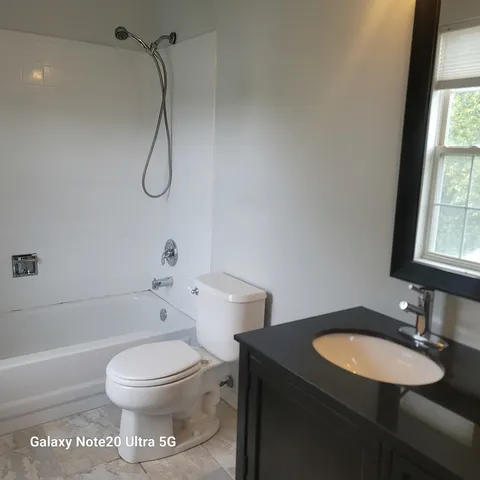 a bathroom with a granite countertop sink toilet a shower and a mirror
