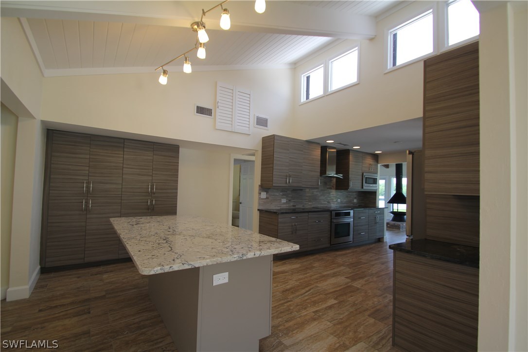 21521 Madera Road Fort Myers Beach, FL 33931 - Photo 17 of 24 a kitchen with stainless steel appliances kitchen island granite countertop a table and chairs in it