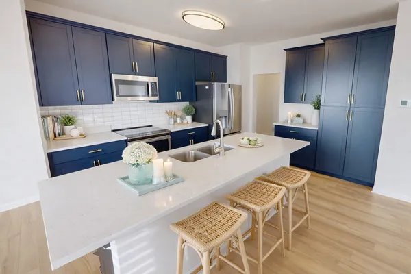 a kitchen with stainless steel appliances kitchen island granite countertop a refrigerator a stove a sink and dishwasher with wooden floor