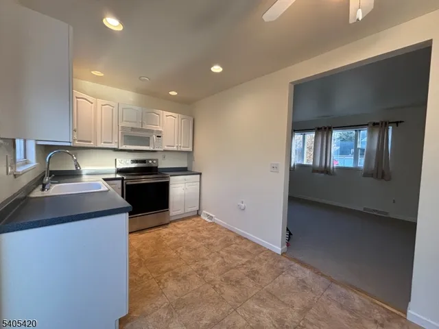 a kitchen with kitchen island granite countertop stainless steel appliances stove sink and cabinets