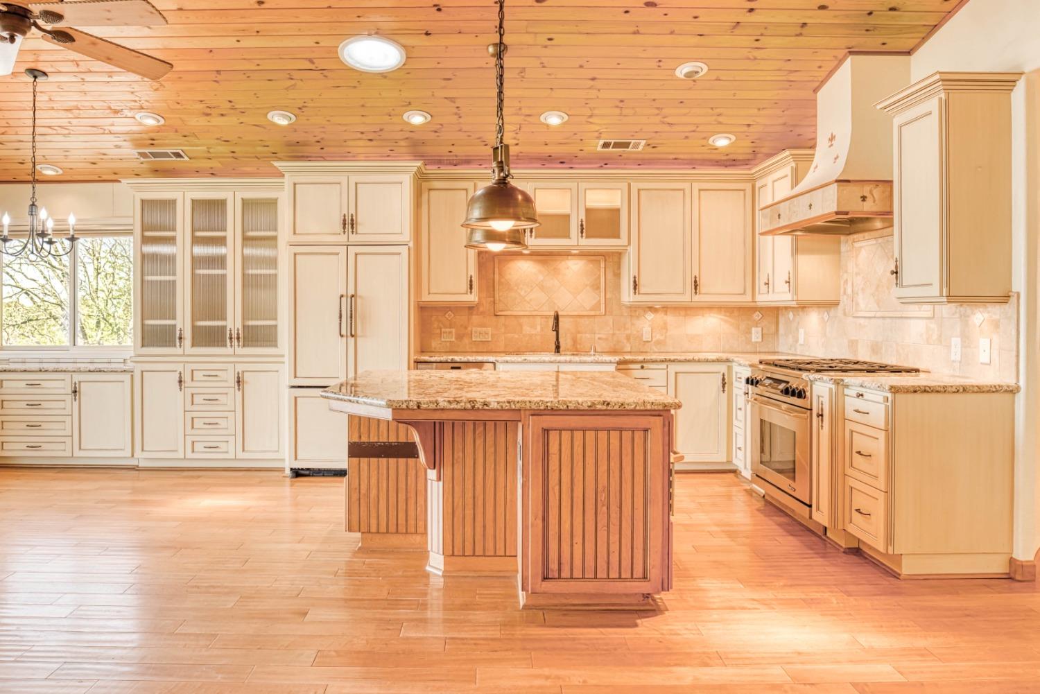 34201 Natoma Road Auberry, CA 93602 - Photo 6 of 40 a kitchen with stainless steel appliances granite countertop a stove top oven a sink a dining table and chairs with wooden floor
