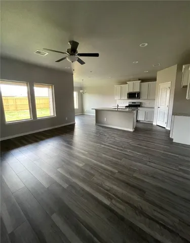 a view of kitchen and empty room with wooden floor