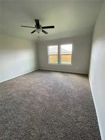an empty room with a ceiling fan and windows