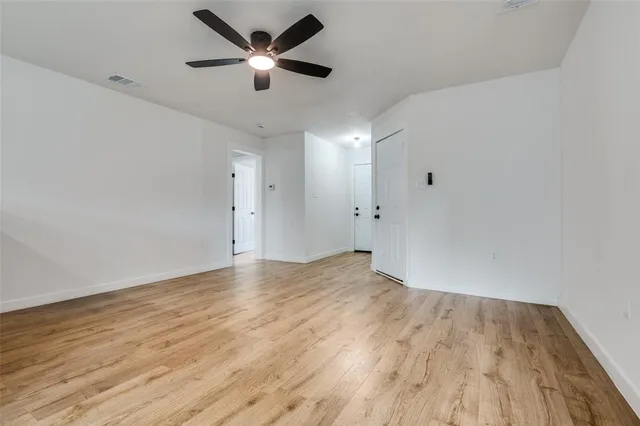an empty room with wooden floor and a ceiling fan