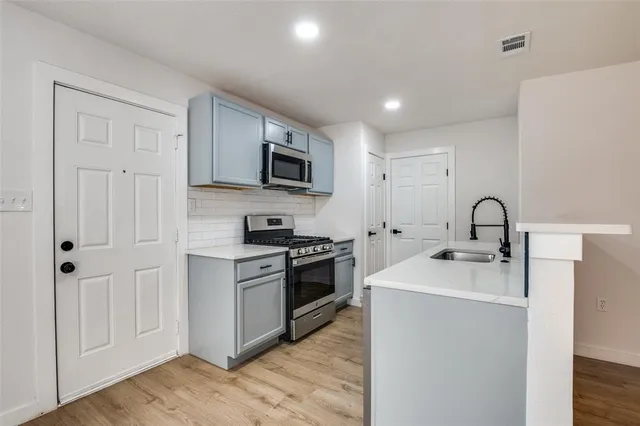 a kitchen with stainless steel appliances granite countertop a sink and a stove top oven with wooden floor