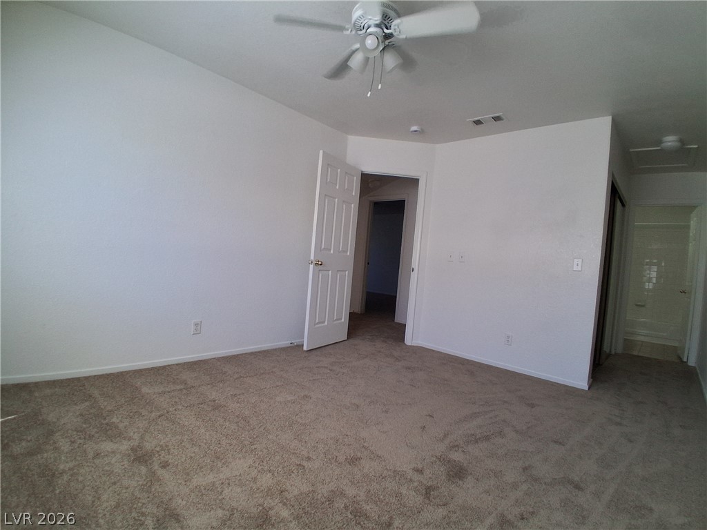 8023 Simone Avenue Las Vegas, NV 89147 - Photo 8 of 12 A spacious bedroom features plush carpeting and a cooling ceiling fan.