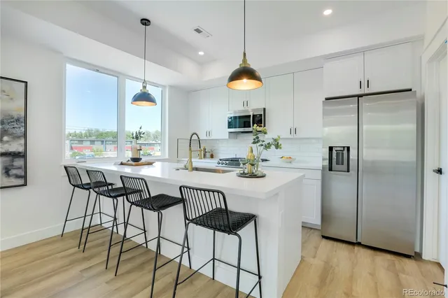 a kitchen with stainless steel appliances a dining table chairs refrigerator and sink