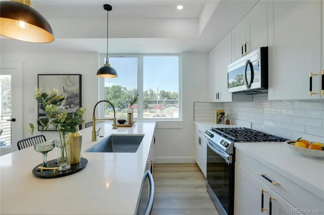 a kitchen with stainless steel appliances granite countertop a sink a stove and a wooden floors