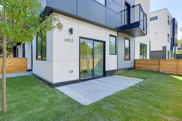 a view of a white house with a big yard potted plants and large tree