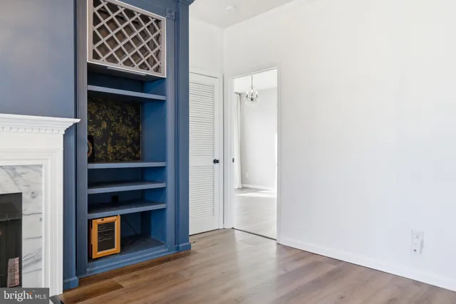 a view of an empty room with wooden floor and a fireplace