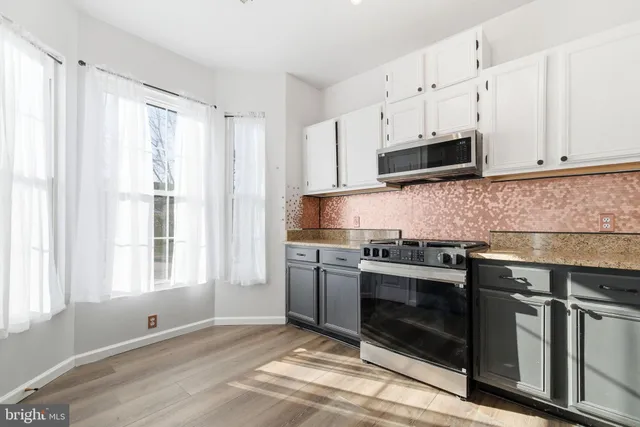 a kitchen with stainless steel appliances granite countertop a stove a sink and a microwave