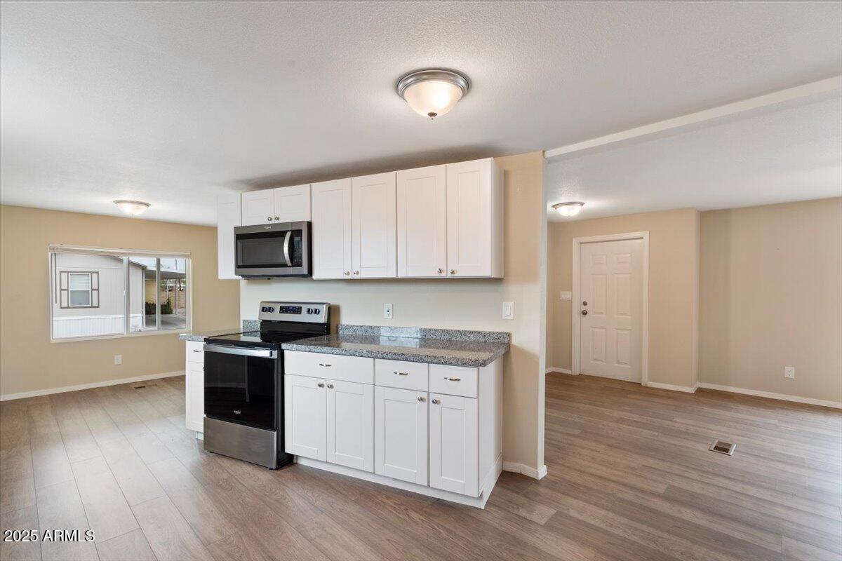 320 East McKellips Road, Unit 211 Mesa, AZ 85201 - Photo 13 of 27 a kitchen with stainless steel appliances granite countertop a stove top oven a sink dishwasher and a microwave oven with wooden floor