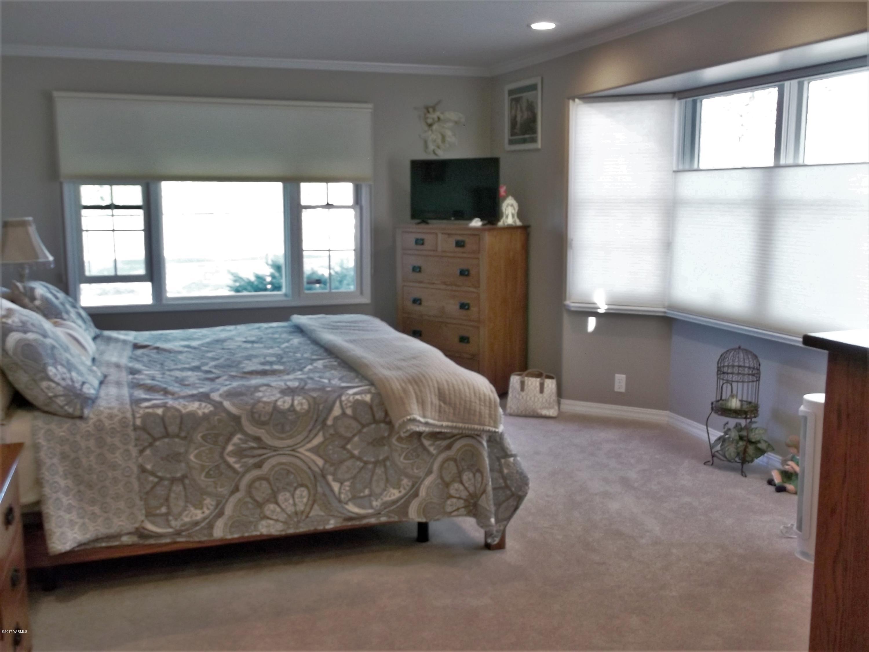 2000 Hornby Road Grandview, WA 98930 - Photo 10 of 45 a spacious bedroom with a bed and a flat tv screen on dresser