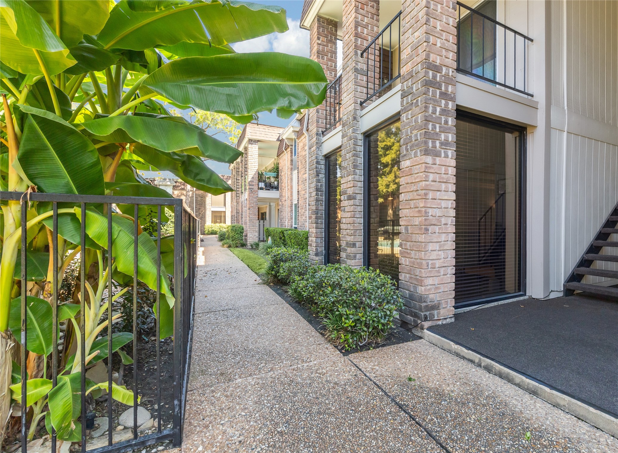 7555 Katy Freeway, Unit 50 Houston, TX 77024 - Photo 2 of 13 a view of yellow house with a yard and plants
