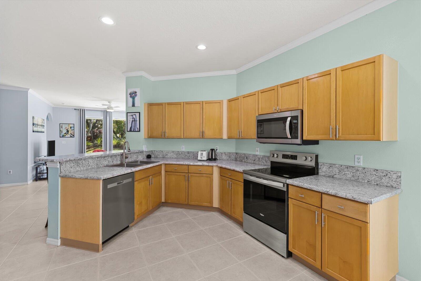 311 Southwest Coconut Key Way Port St. Lucie, FL 34986 - Photo 10 of 25 a kitchen with stainless steel appliances granite countertop a stove top oven a sink dishwasher and a refrigerator with wooden cabinets