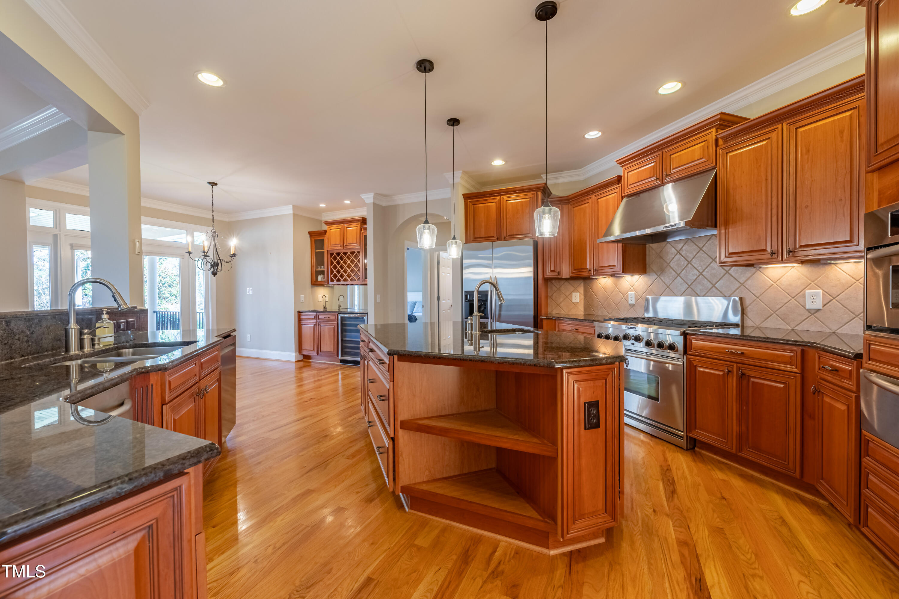 1408 Goldengate Court Raleigh, NC 27613 - Photo 17 of 64 a large kitchen with stainless steel appliances kitchen island granite countertop a large kitchen island a stove a refrigerator a sink a dining table and chairs with wooden floor