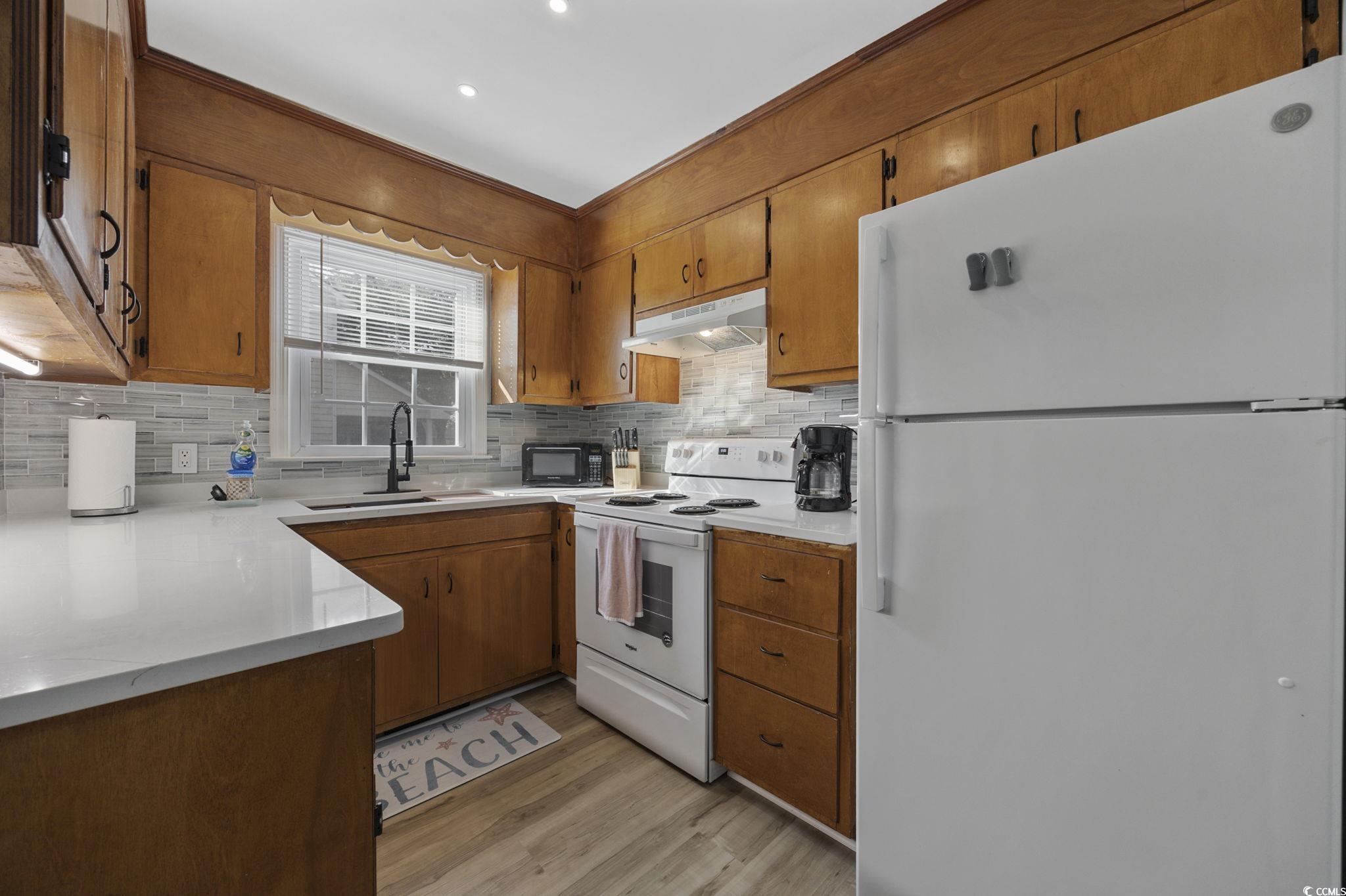 787 Causey Road Murrells Inlet, SC 29576 - Photo 9 of 40 Kitchen with white appliances, brown cabinets, under cabinet range hood, and decorative backsplash