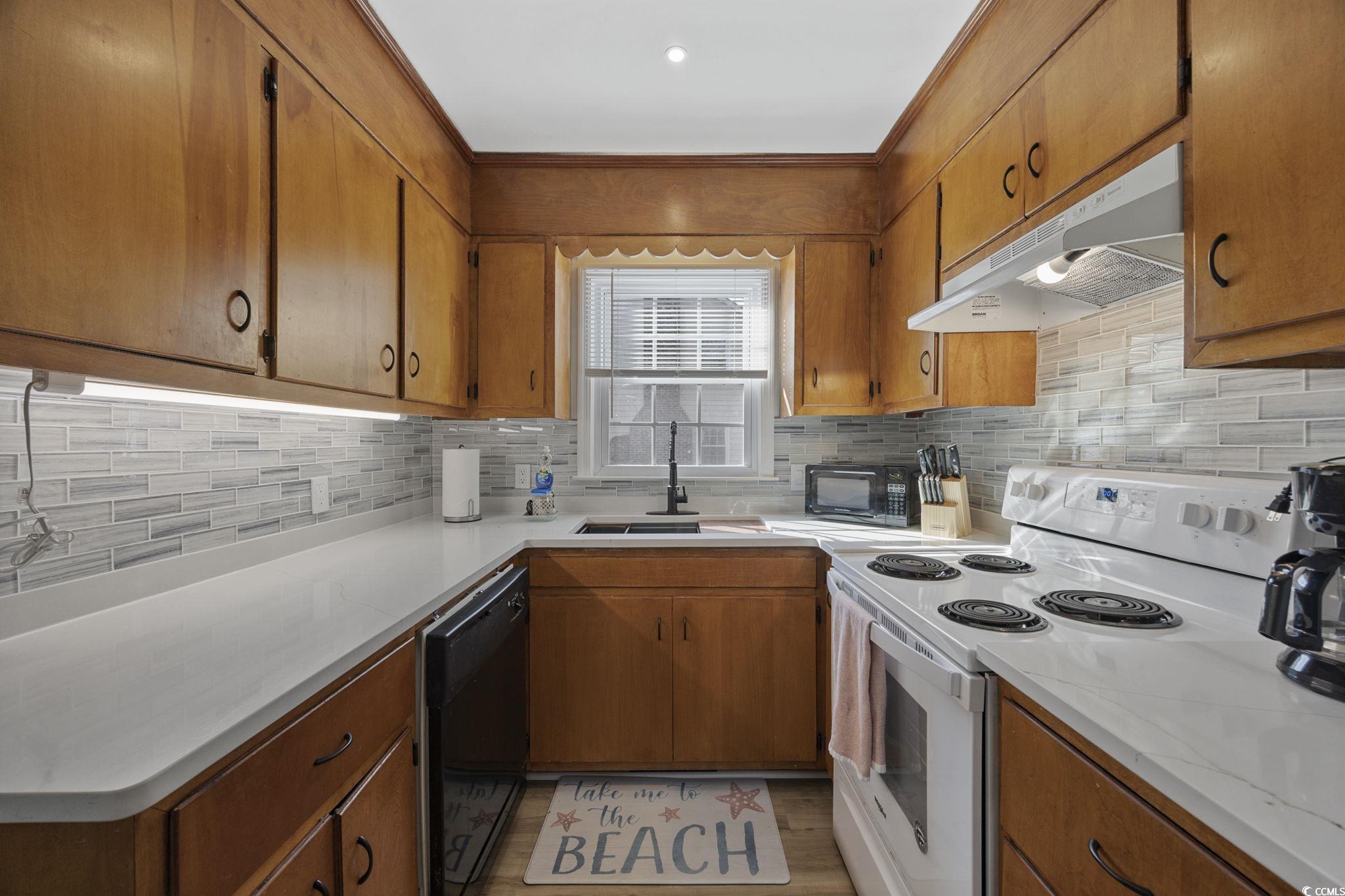 787 Causey Road Murrells Inlet, SC 29576 - Photo 10 of 40 Kitchen featuring black appliances, brown cabinetry, under cabinet range hood, tasteful backsplash, and light wood-style floors
