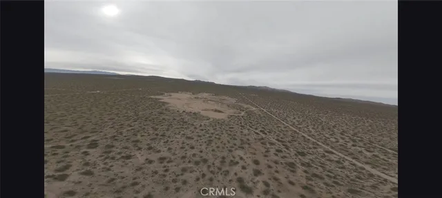 a view of a dry yard with mountains in the background
