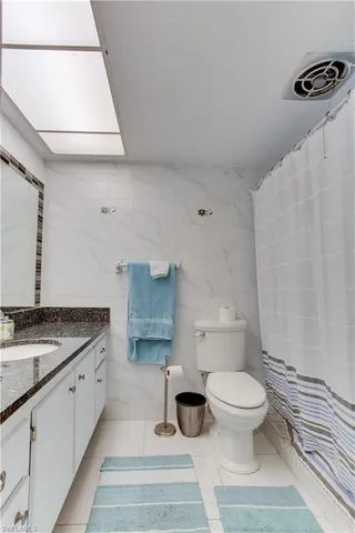 a bathroom with a granite countertop sink a toilet and a mirror