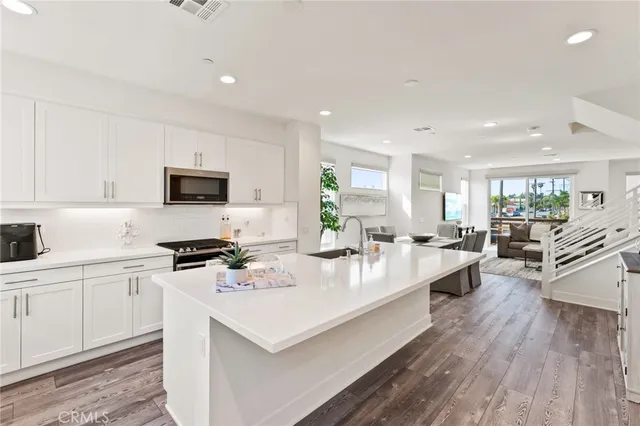 a large white kitchen with cabinets a sink a stove a dining table and chairs