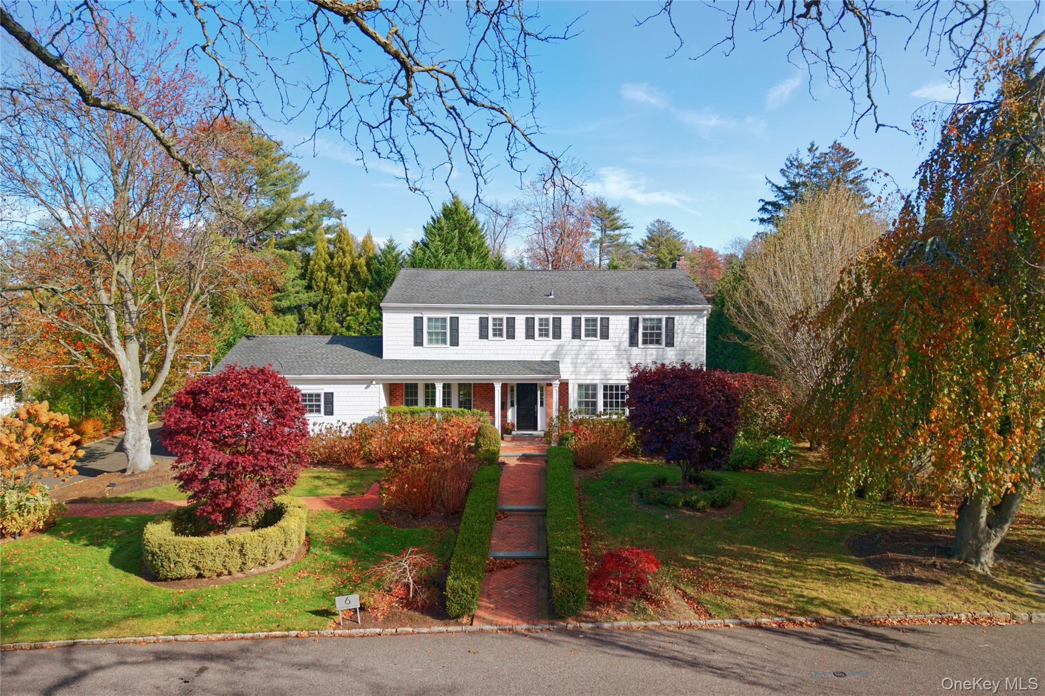 a front view of a house with a garden and tree