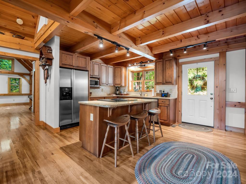 1065 South Cove Road Mill Spring, NC 28756 - Photo 9 of 48 a kitchen with stainless steel appliances kitchen island granite countertop a table chairs and wooden floor