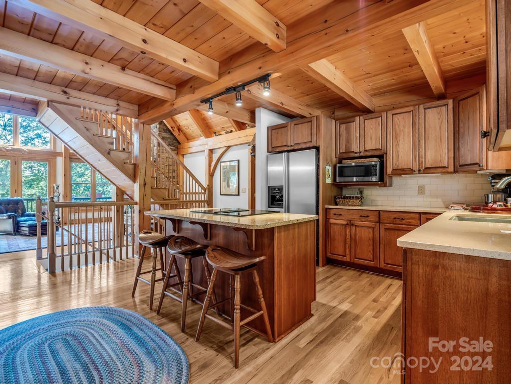 1065 South Cove Road Mill Spring, NC 28756 - Photo 10 of 48 a kitchen with stainless steel appliances granite countertop a stove a refrigerator a dining table and chairs with wooden floor