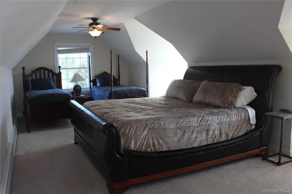a spacious bedroom with a bed a dresser and mirror