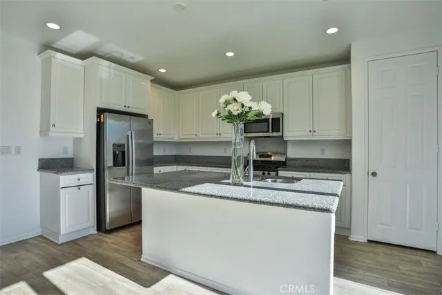 a kitchen with stainless steel appliances granite countertop a sink a stove and a refrigerator