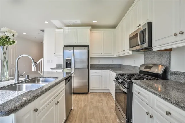 a kitchen with stainless steel appliances granite countertop a sink stove microwave and refrigerator