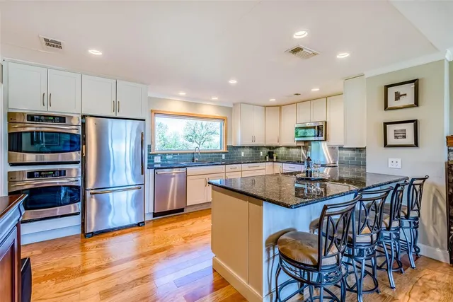 a kitchen with stainless steel appliances granite countertop a refrigerator and a stove top oven