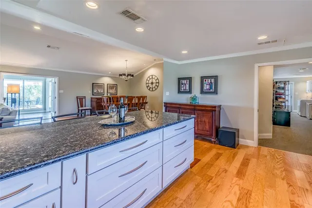 a kitchen with stainless steel appliances granite countertop wooden cabinets a sink a stove a dining table and chairs