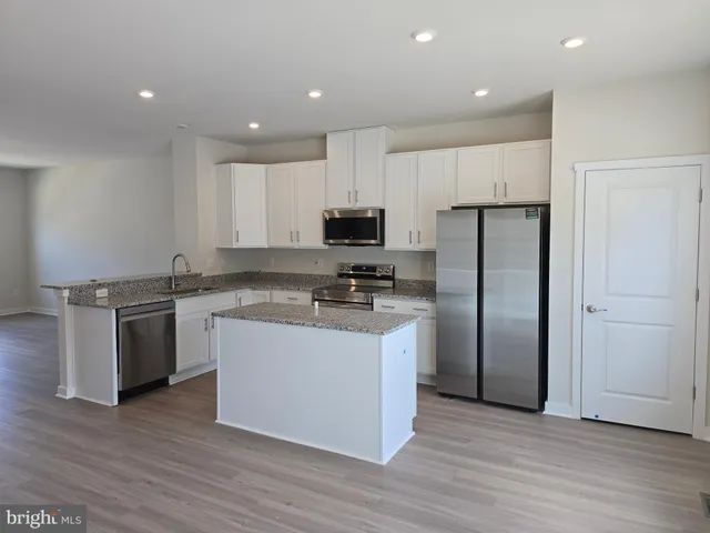 a large kitchen with stainless steel appliances granite countertop a stove a refrigerator and a microwave