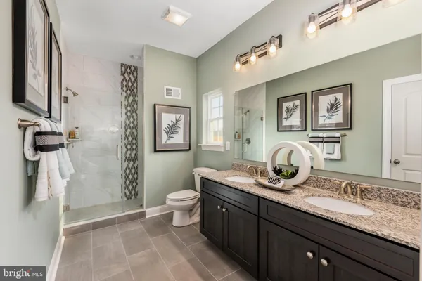 a bathroom with a granite countertop sink a toilet a mirror and shower