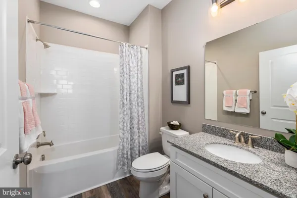 a bathroom with a granite countertop tub sink toilet and mirror